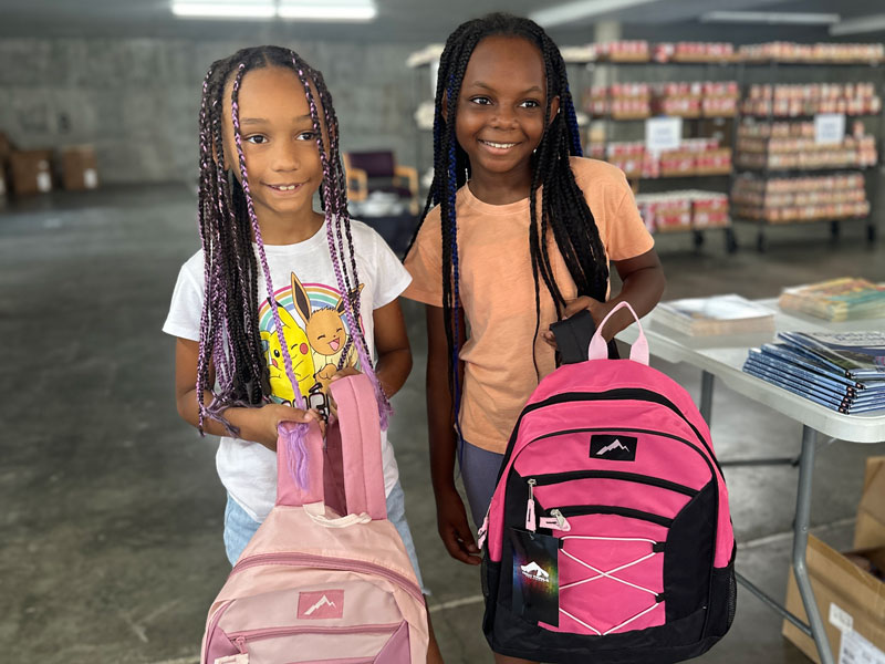 2 kids receiving backpacks